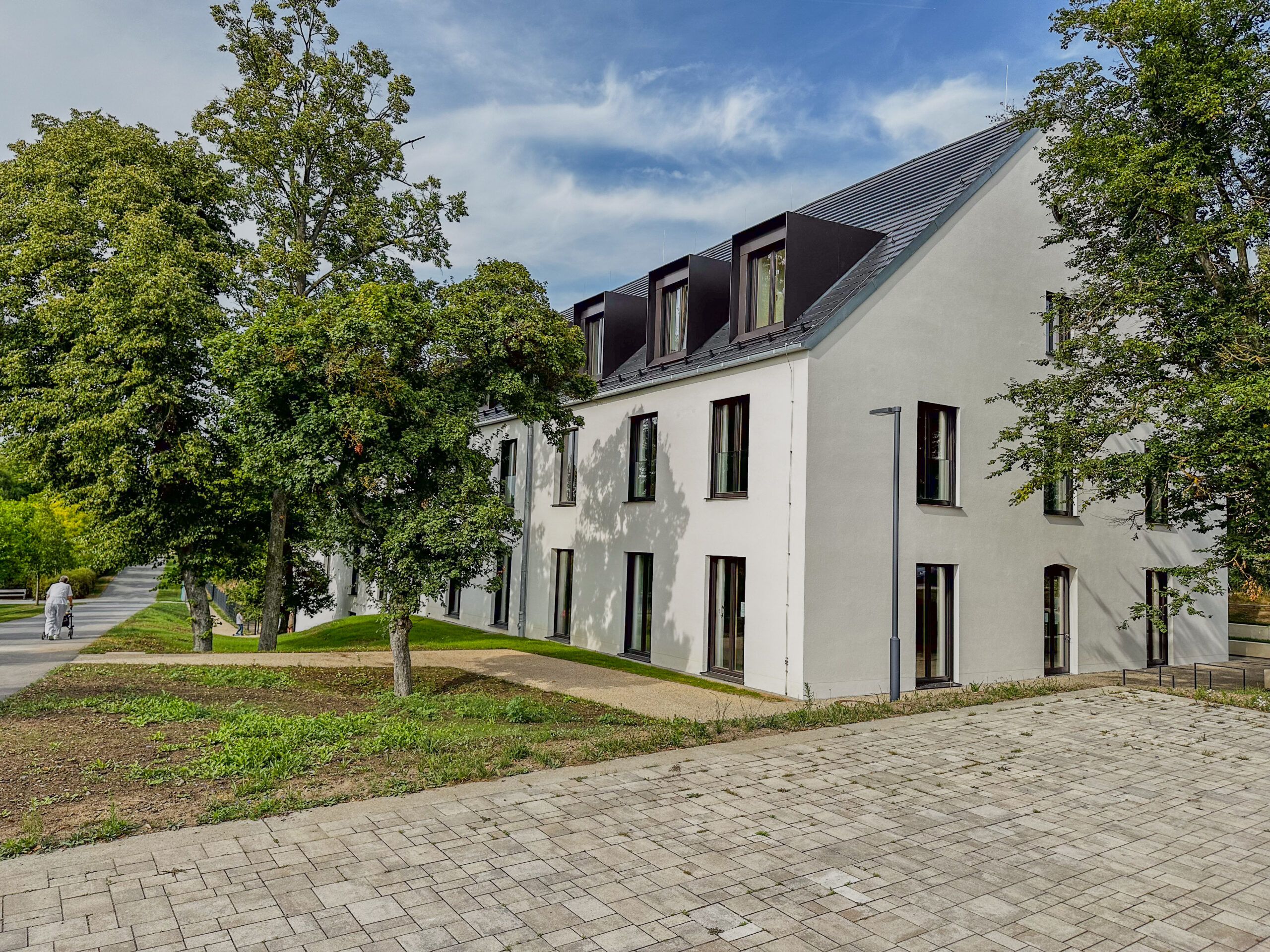 Ein Wohnhaus im Stadtteil Hubland. Vorn eine gepflasterte Einfahrt und frisch bepflanzte Vorgärten.