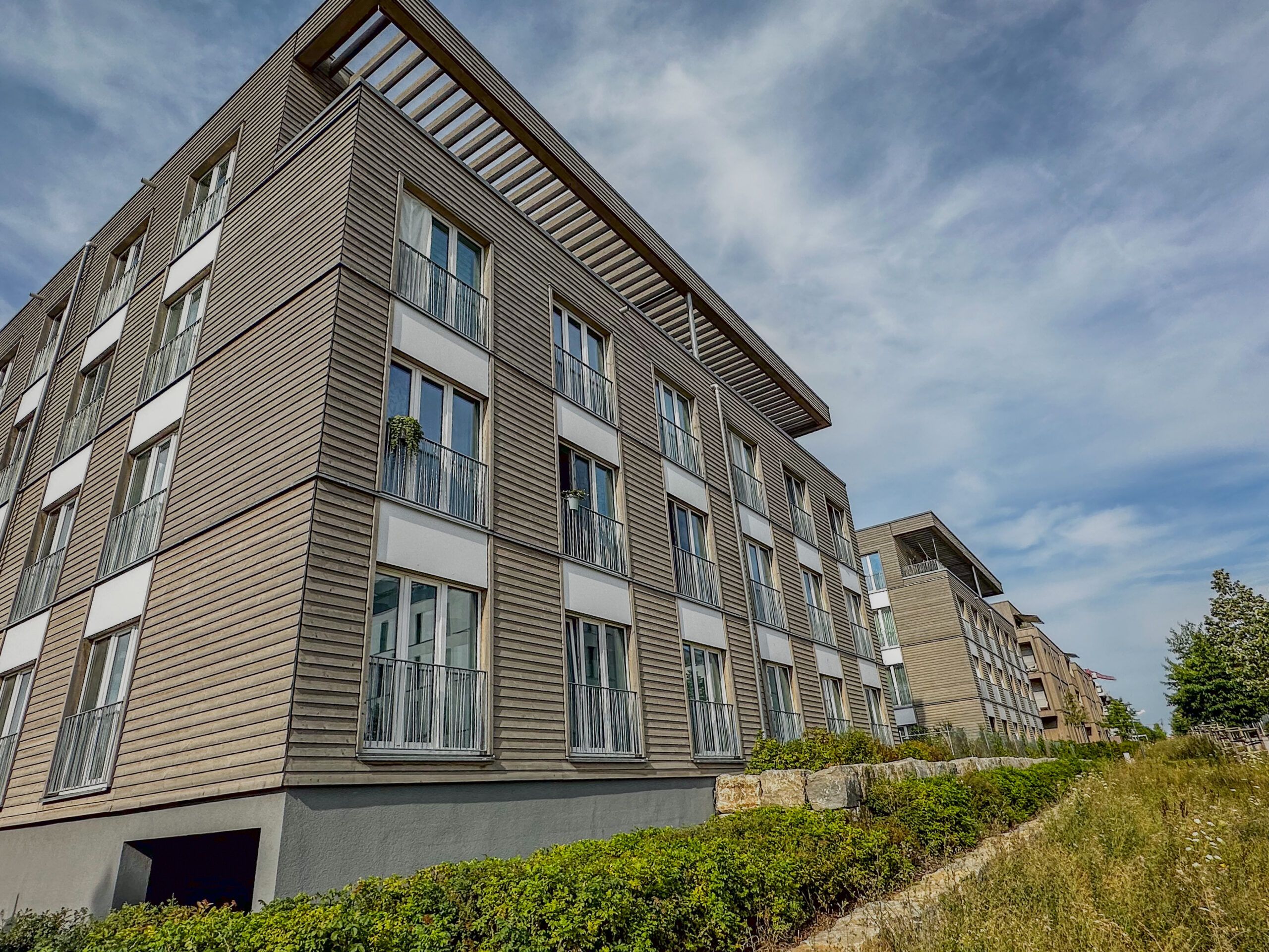 Moderne Wohnhäuser des neuen Stadtteils Hubland in Würzburg. Die Häuser haben ein Holzoptik und große Fenster mit flachen Dächern.